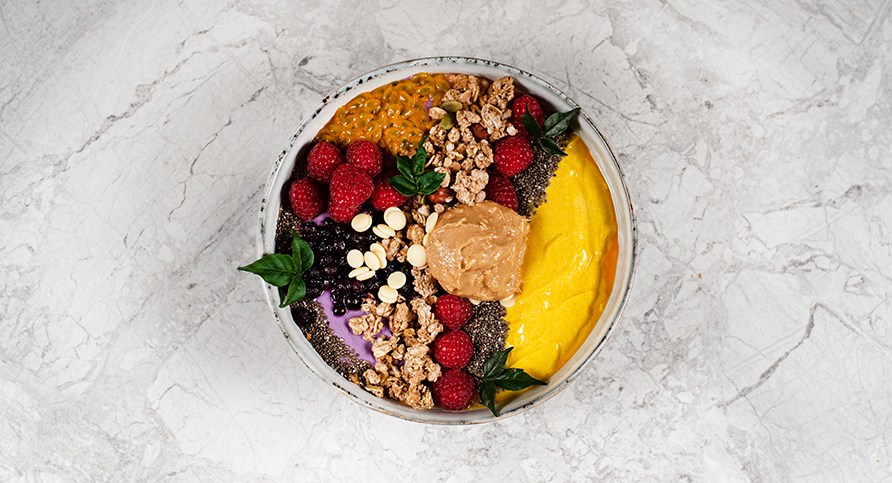 En smoothie bowl med blandet frugter og ndder som topping, samt peanutbutter.